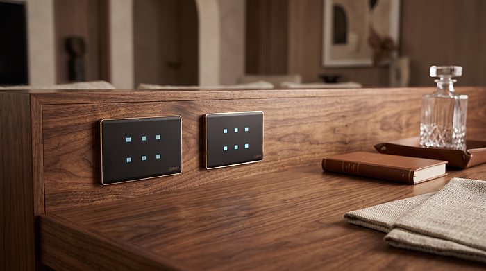 Two black Cubixx touch panels with gold frames, set into walnut joinery, keys lit.